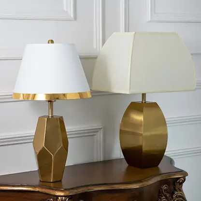 Gold faceted table lamps with white tapered shades shown together with lights off highlighting elegant geometric bases for modern home styling.