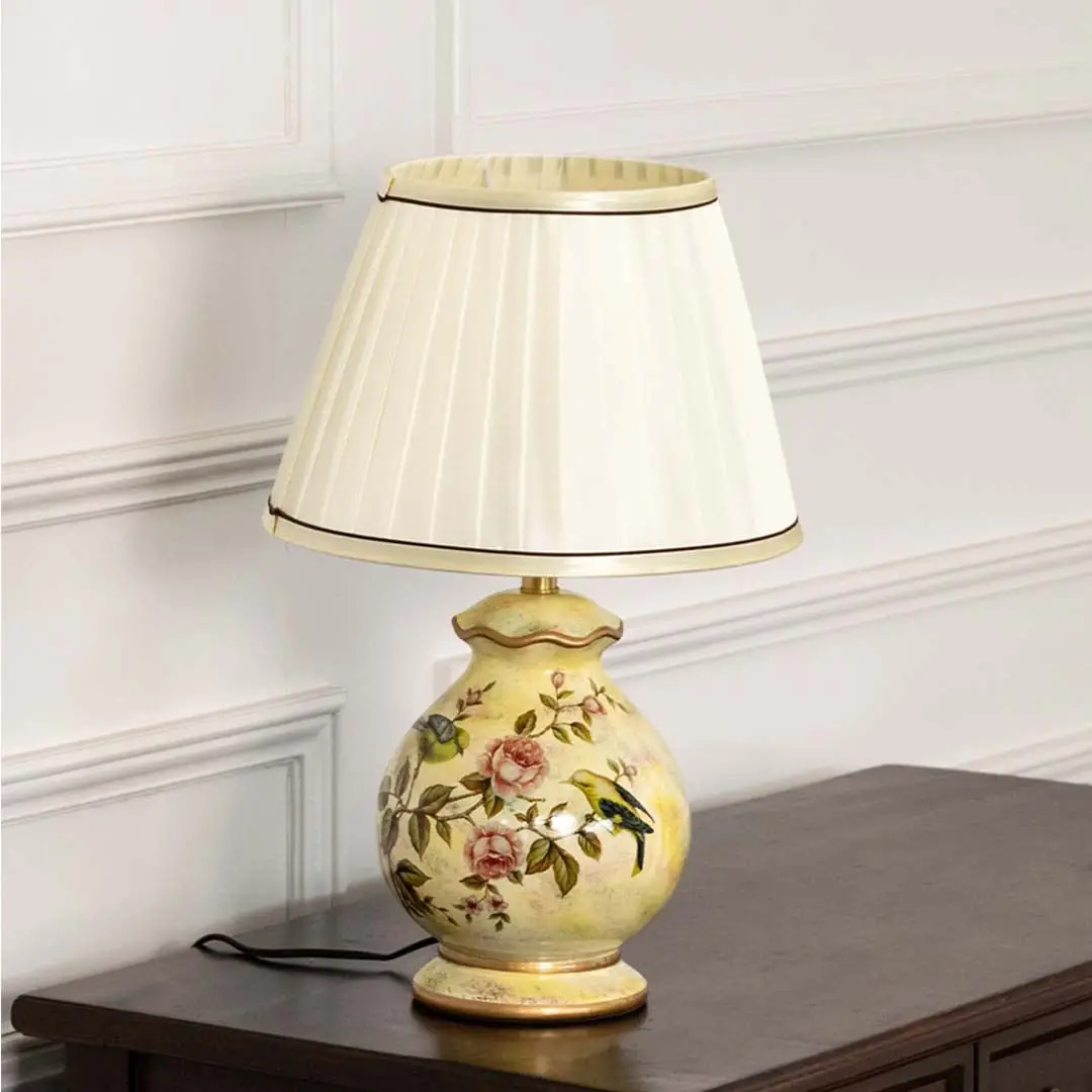 Unlit floral ceramic lamp with gold base and white pleated shade highlights its graceful silhouette and exquisite painted craftsmanship.