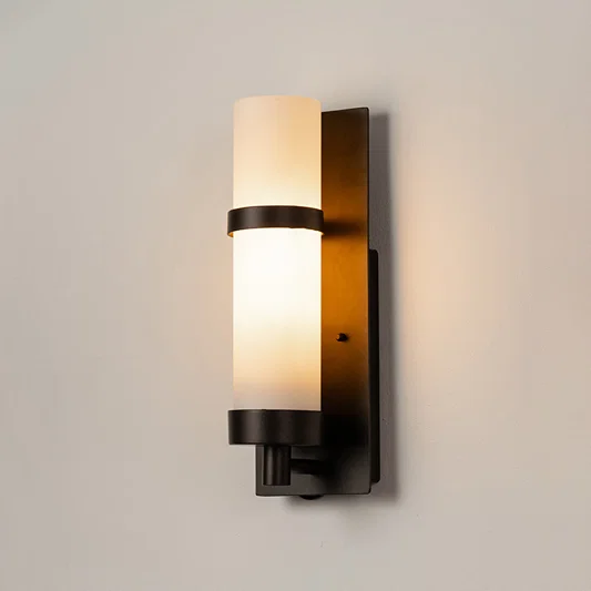 Black metal wall light on white background with frosted glass shade for elegant modern exterior decor.