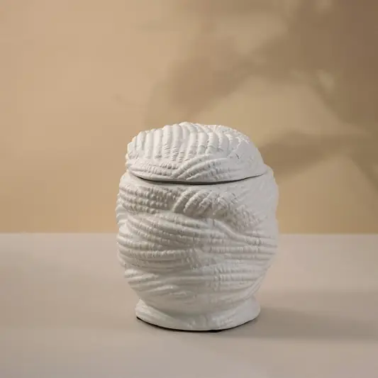 Handcrafted white ceramic vase with a textured pattern glowing gently under light on white background showing artistic craftsmanship.