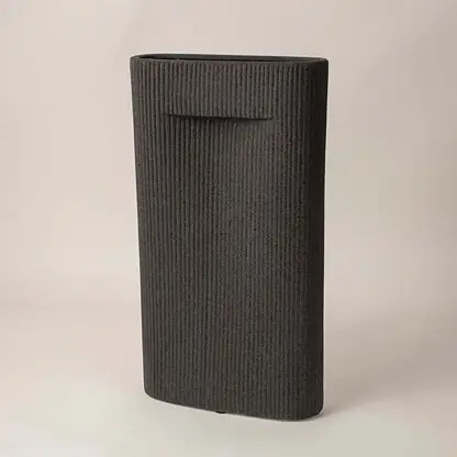 Ribbed black ceramic vase with soft matte finish placed side way showcasing its bold modern silhouette.