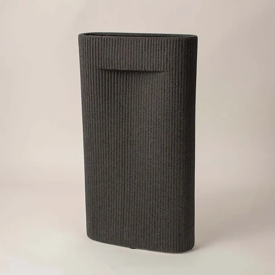 Ribbed black ceramic vase with soft matte finish placed side way showcasing its bold modern silhouette.