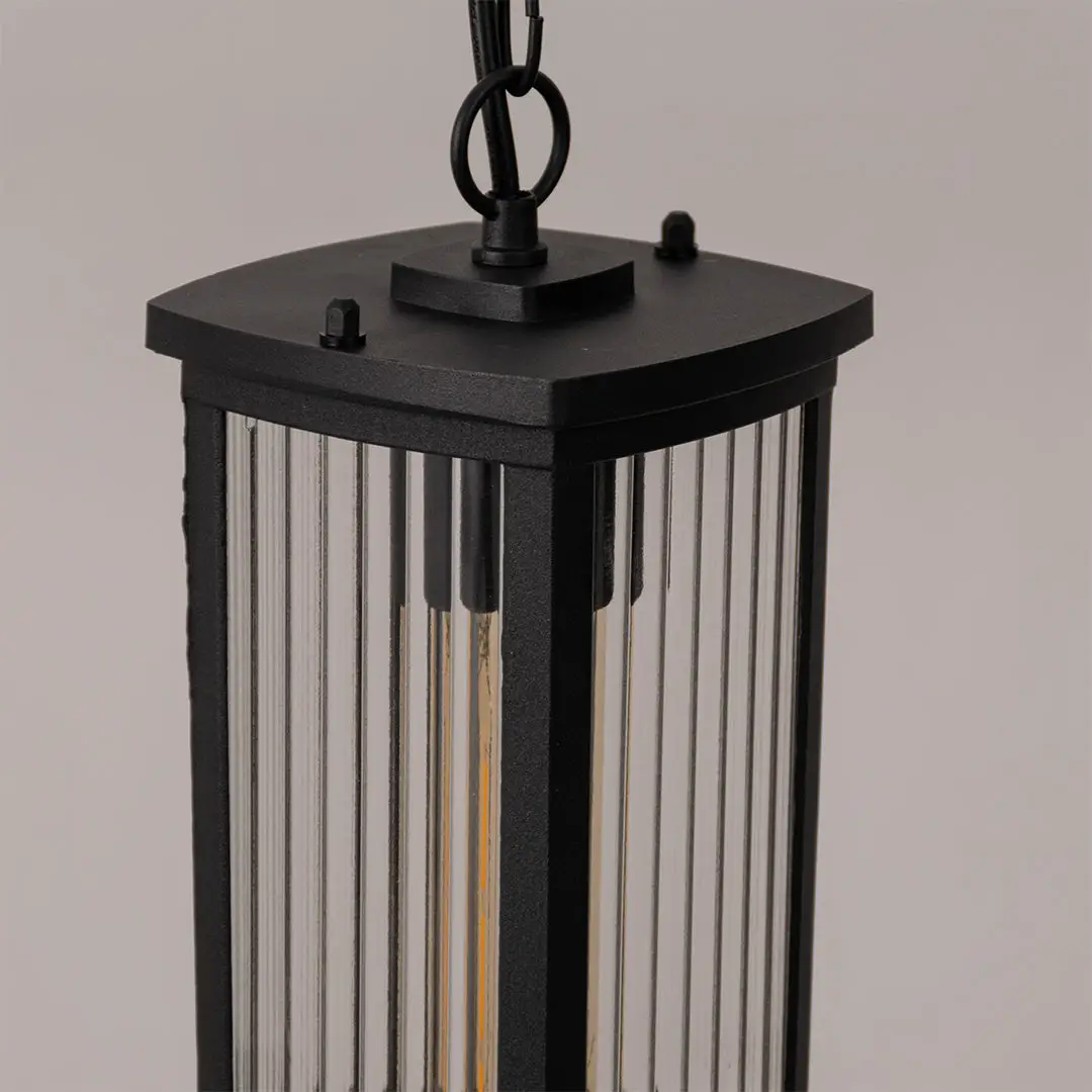Closeup outdoor lantern in black metal finish with ribbed glass panels for garden or entrance decor lighting white background.