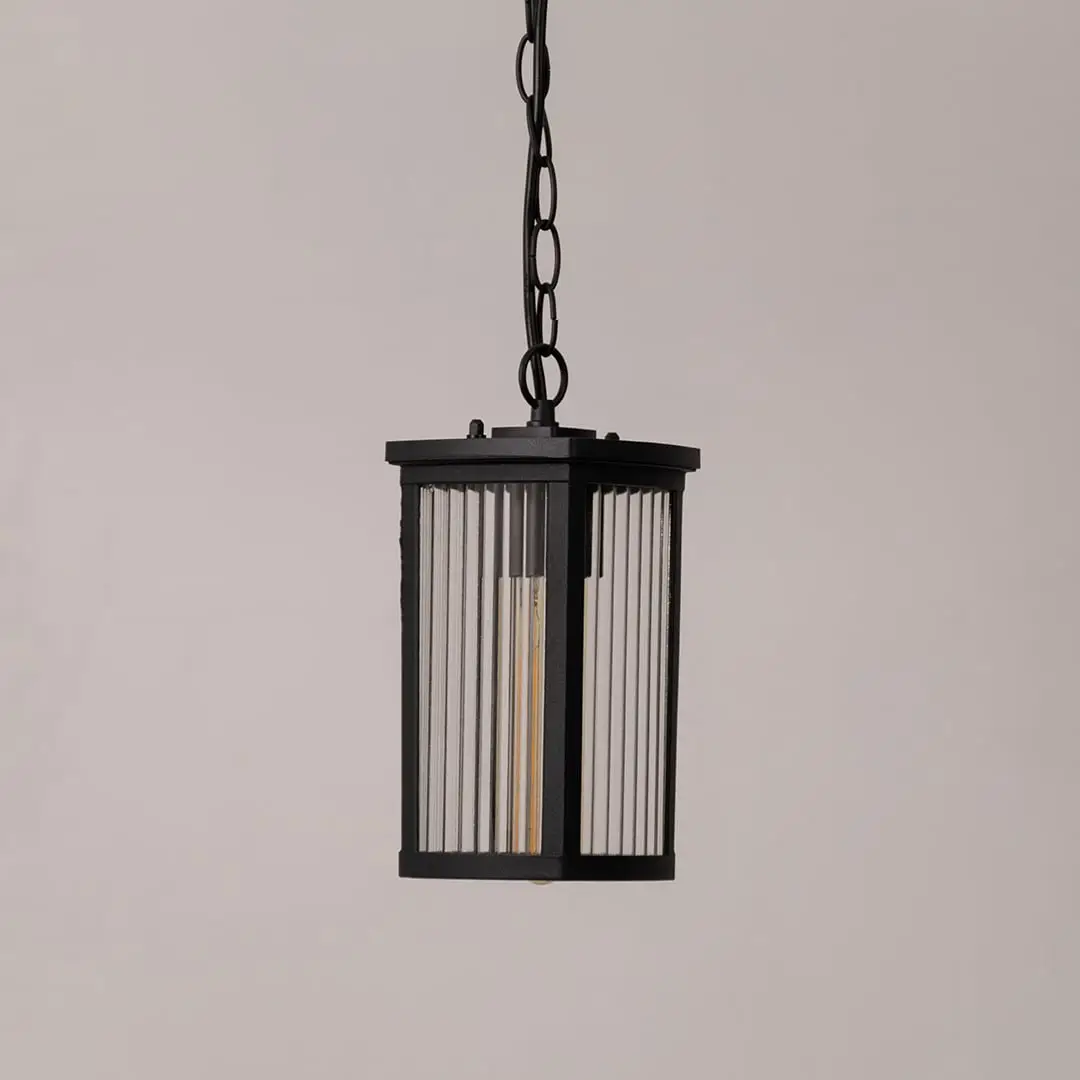 Black metal lantern with ribbed glass shown on white background displaying sleek outdoor lighting design.