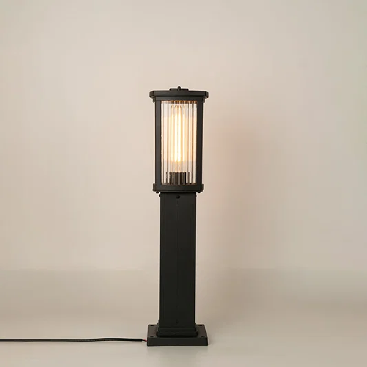 Modern black outdoor bollard light with warm glowing panels for stylish exterior decor use.