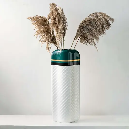 Decorative tall vase featuring a green top and white textured body placed in a bright setting to highlight its stylish shape and modern design appeal.
