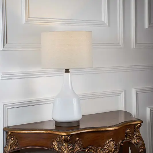 White fabric shade table lamp with glossy white ceramic base and gold accents for luxury bedside and console styling.