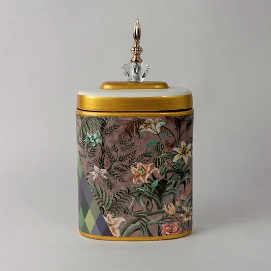 Decorative ceramic jar with floral botanical artwork and gold lid placed on white surface against neutral background showcasing luxury artistic home decor styling.