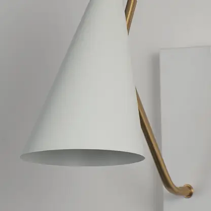 Elegant wall light with matte white conical shade and slim gold arm in closeup view highlighting minimal contemporary design.