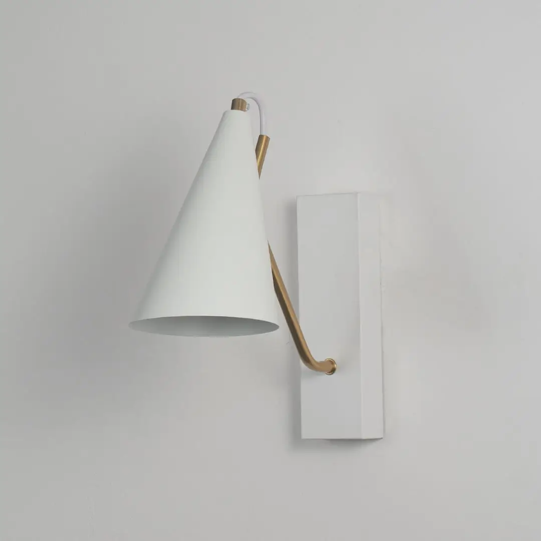 White wall light with conical shade and gold arm shown off on white background for modern bedroom and living room decor.