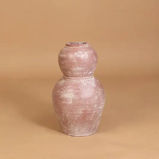 Decorative ceramic vase in pink finish with textured pattern for table decor or shelf styling modern home placement neutral background.