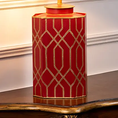 Table lamp closeup highlighting red ceramic base with gold geometric design and smooth glossy surface.
