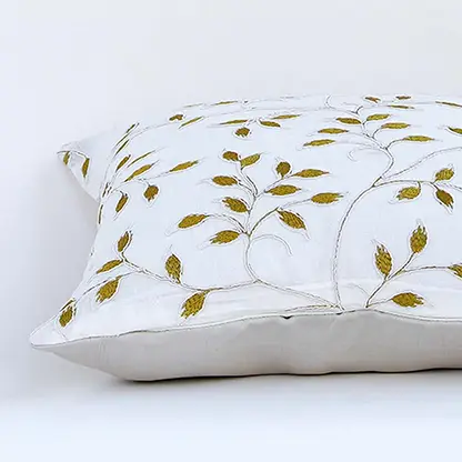 White cotton cushion cover with golden leaf embroidery in a rectangular form adding an elegant natural décor detail with a soft comfortable and skin friendly material.