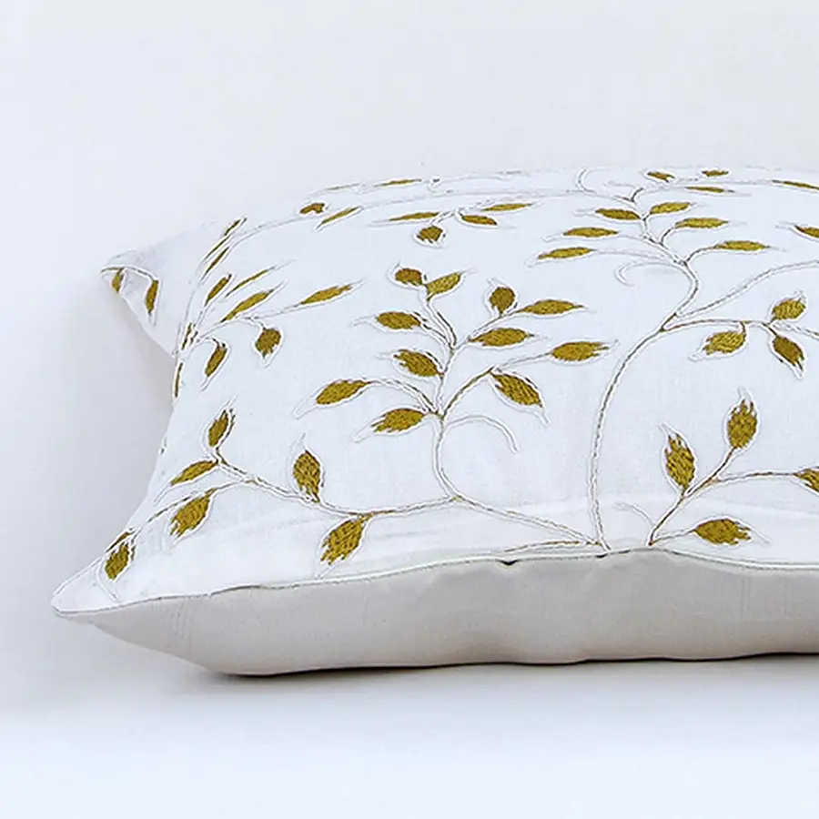 White cotton cushion cover with golden leaf embroidery in a rectangular form adding an elegant natural décor detail with a soft comfortable and skin friendly material.