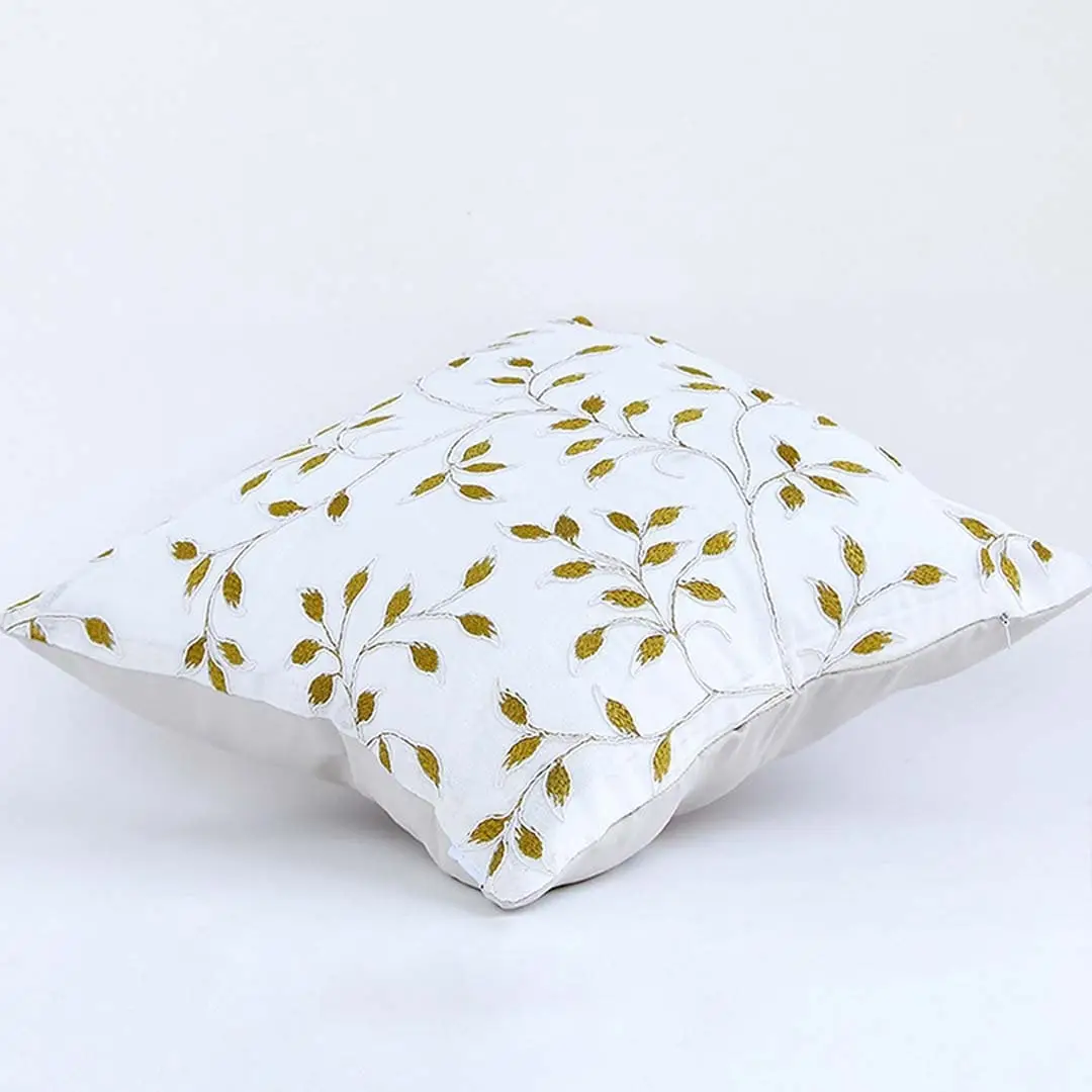 Soft cotton cushion cover with golden botanical embroidery shown at an angle offering a warm nature inspired décor accent with a breathable gentle and skin friendly fabric finish.