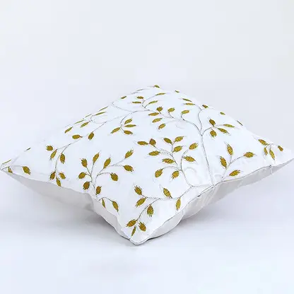 Soft cotton cushion cover with golden botanical embroidery shown at an angle offering a warm nature inspired décor accent with a breathable gentle and skin friendly fabric finish.
