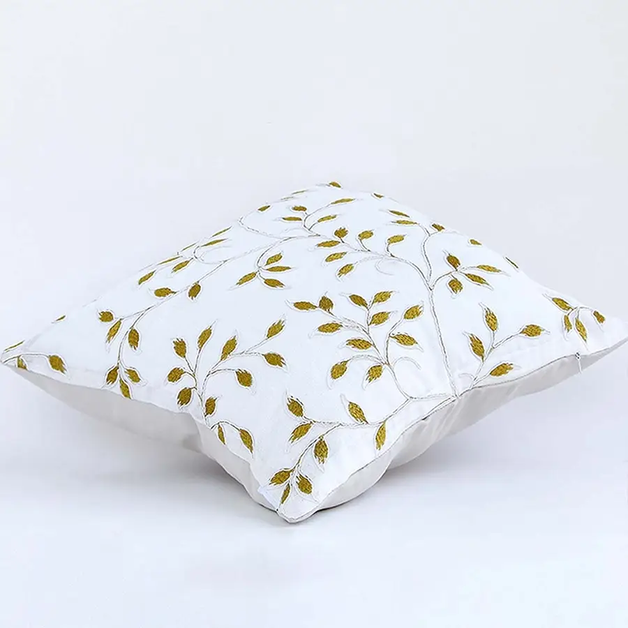 Soft cotton cushion cover with golden botanical embroidery shown at an angle offering a warm nature inspired décor accent with a breathable gentle and skin friendly fabric finish.