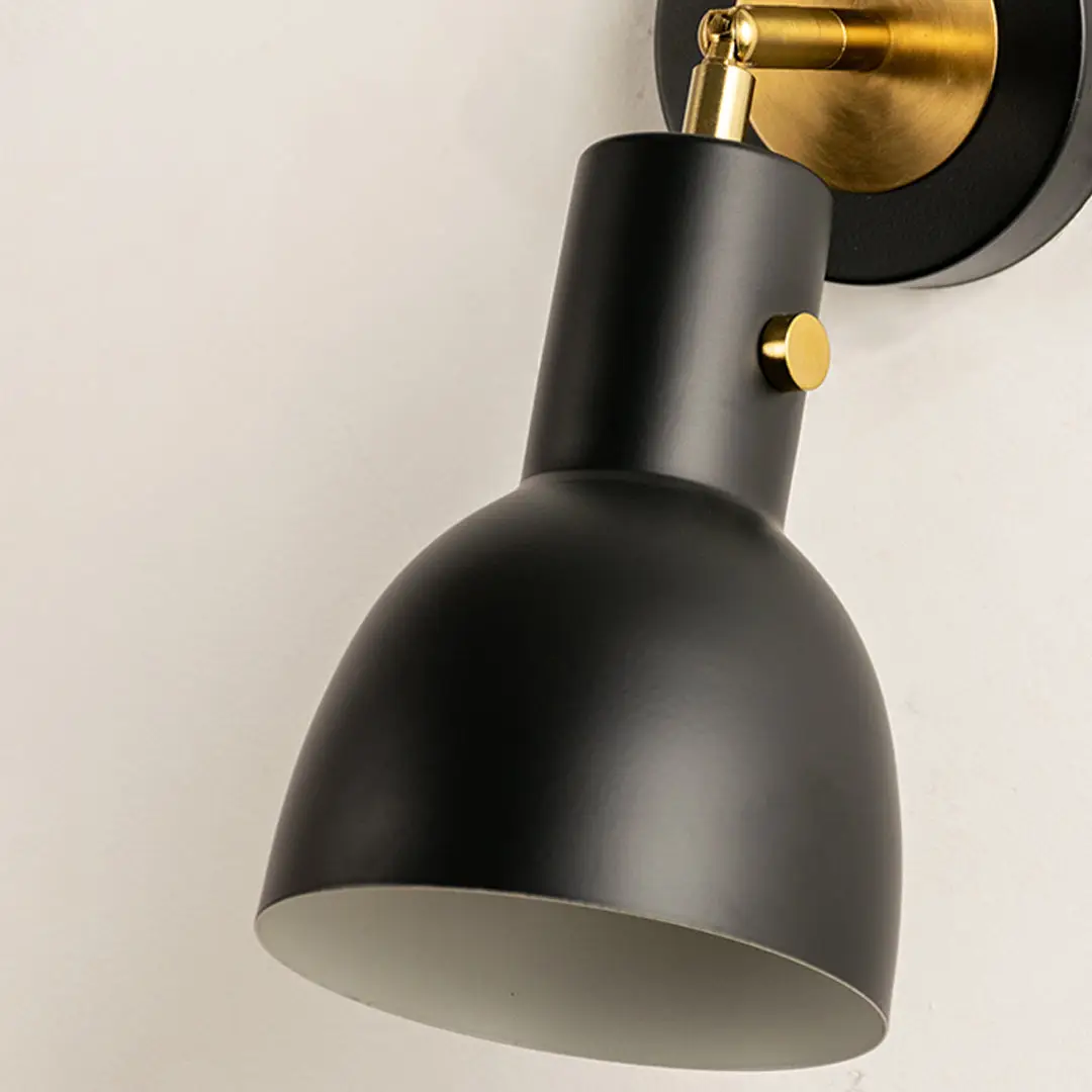 Closeup of gold metal wall light with smooth cone shade for elegant bedroom hallway and modern home decor styling.