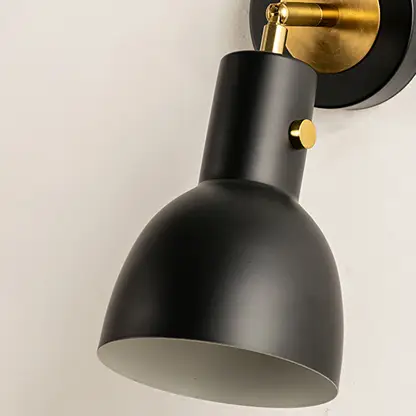 Closeup of gold metal wall light with smooth cone shade for elegant bedroom hallway and modern home decor styling.
