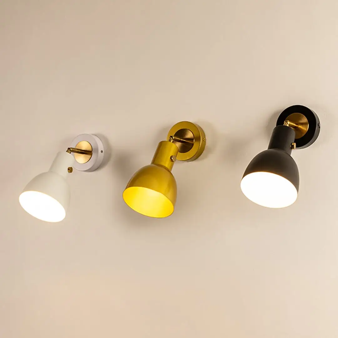 A trio of modern metal wall lights glowing softly in white gold and black finishes against a smooth beige wall adding warm illumination and stylish home décor.