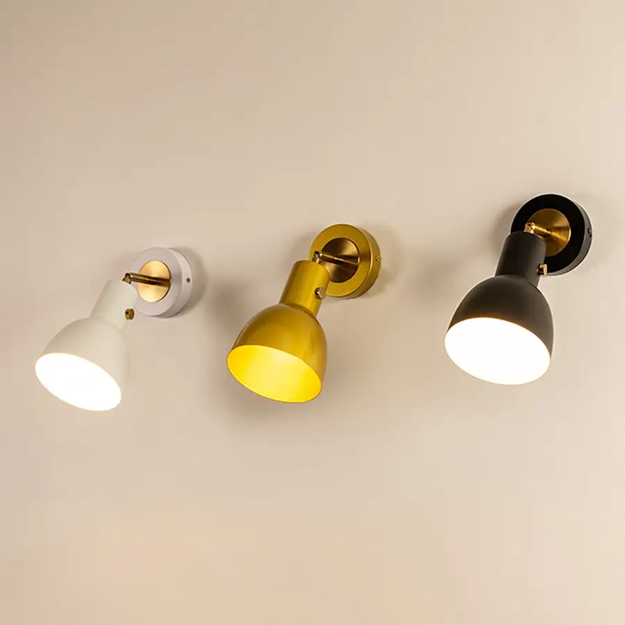 A trio of modern metal wall lights glowing softly in white gold and black finishes against a smooth beige wall adding warm illumination and stylish home décor.