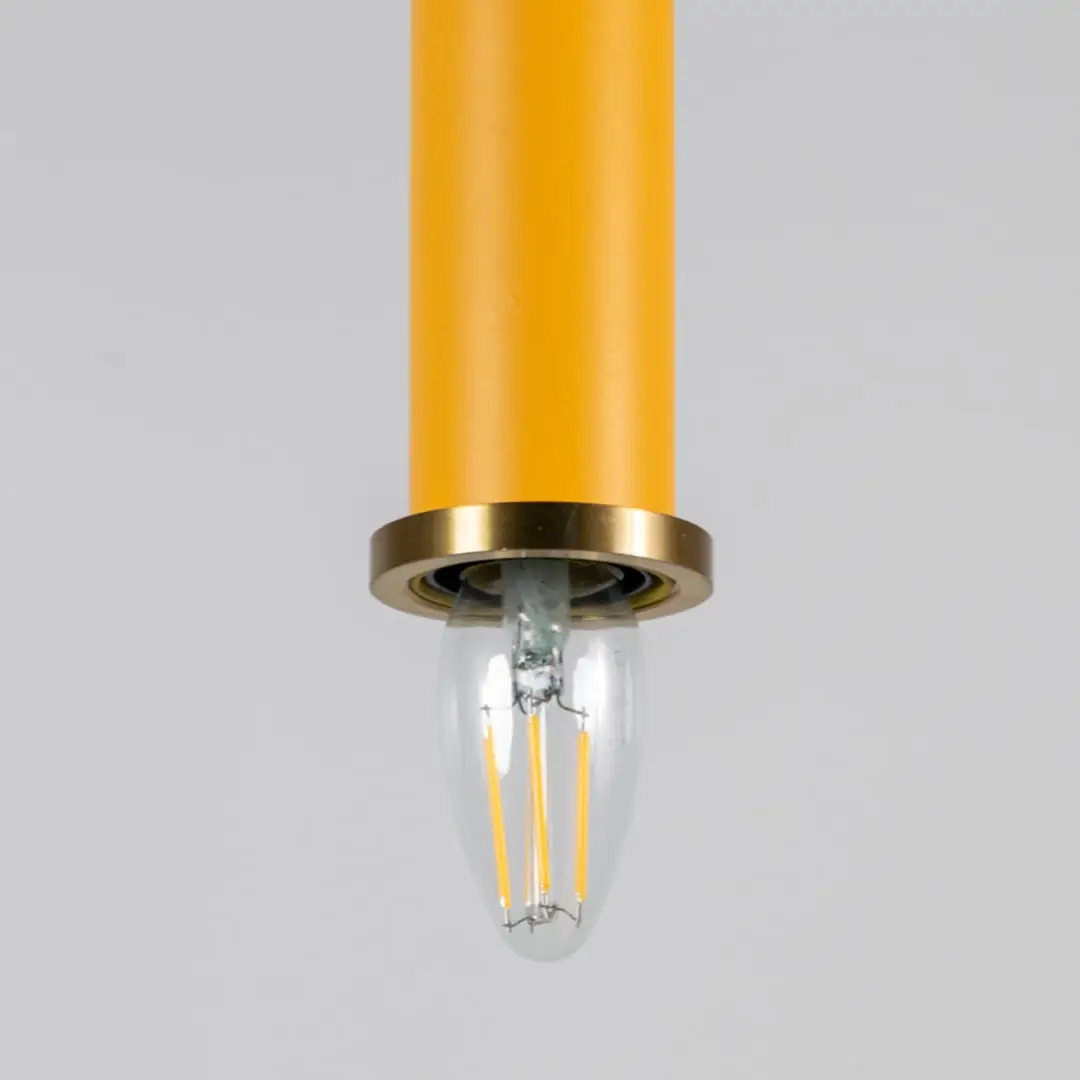 Yellow metal pendant light with brass detailing showcasing sleek cylindrical form and modern Scandinavian style appeal.