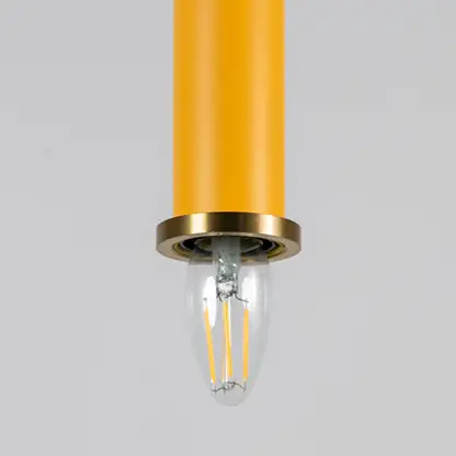 Yellow metal pendant light with brass detailing showcasing sleek cylindrical form and modern Scandinavian style appeal.