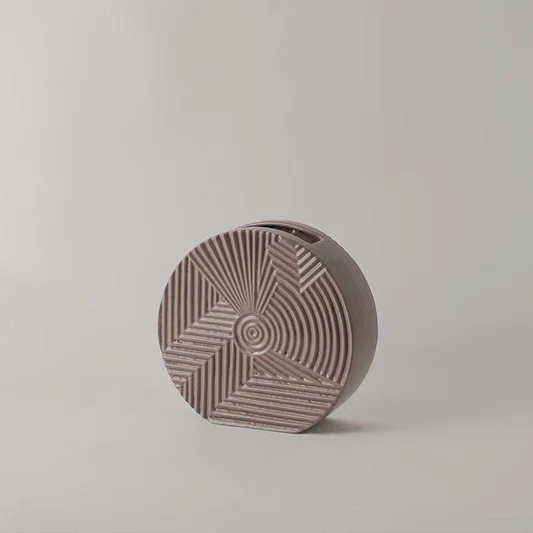 Matte brown round ceramic vase with etched geometric lines standing empty against a clean white background for display.