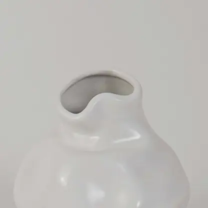 Closeup of white ceramic vase showing smooth glossy texture and curved shape ideal for minimalist decor aesthetics.