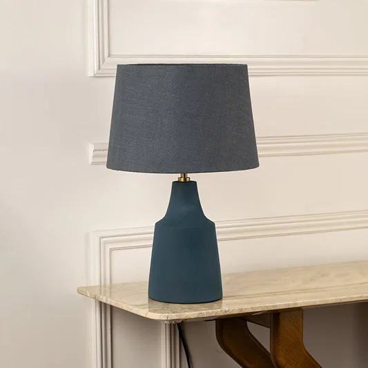Blue ceramic table lamp with black fabric shade and modern silhouette for sophisticated living room decor styling.