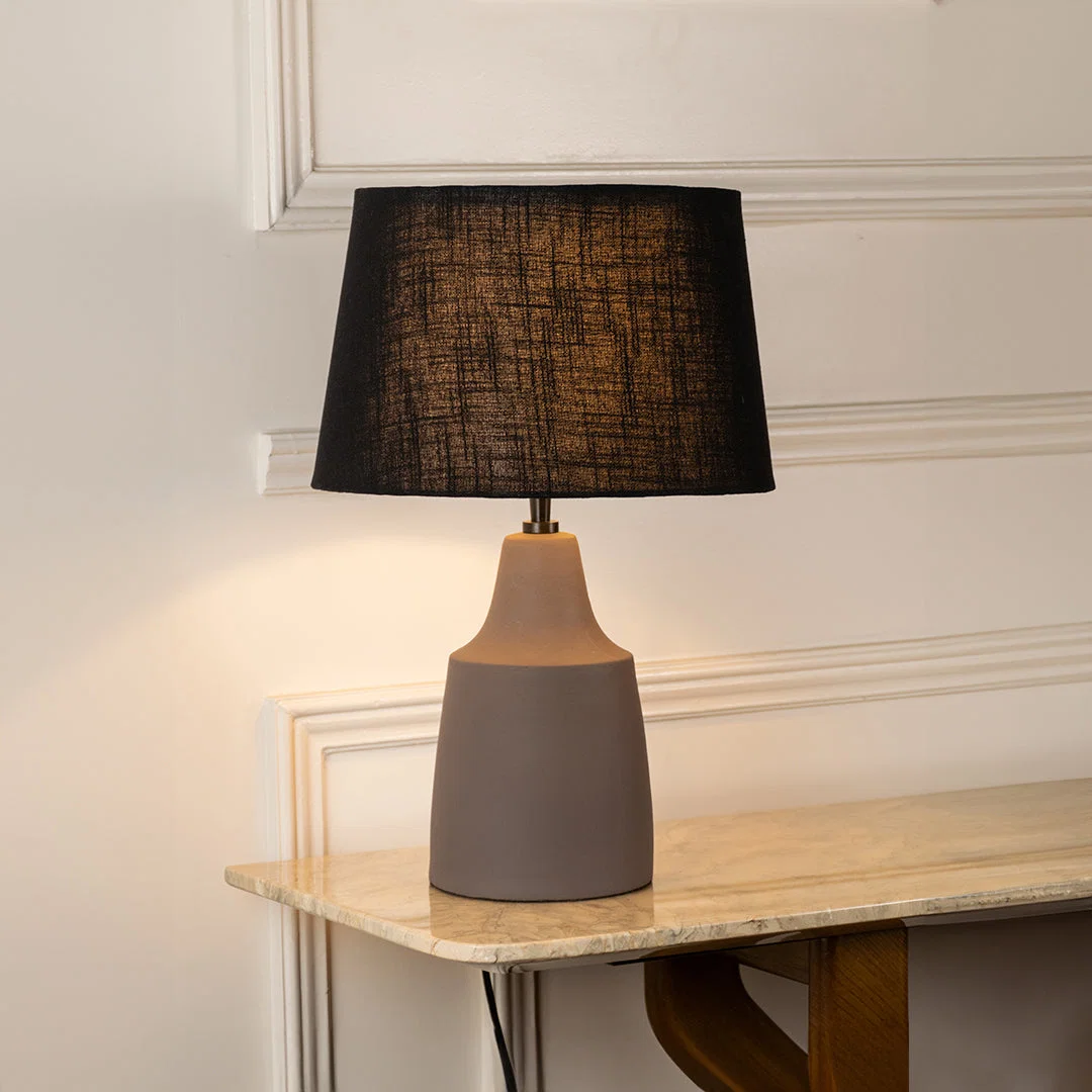Table lamp with dark fabric shade and ceramic base perfect for elegant bedroom or living room table decor styling on clean background.