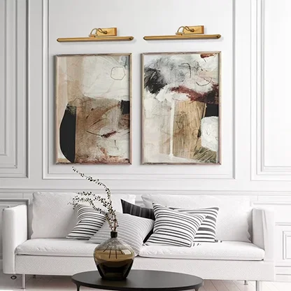 Gold adjustable picture light mounted above artwork creating warm focused illumination for elegant living room and hallway decor.