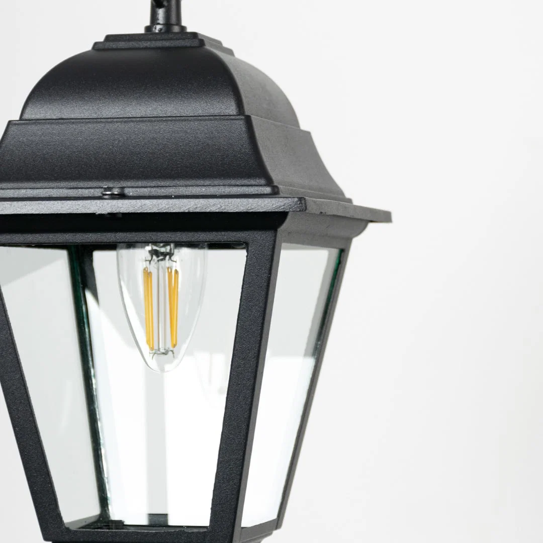 Closeup of outdoor hanging lantern light showing bulb detail and refined black metal finish.