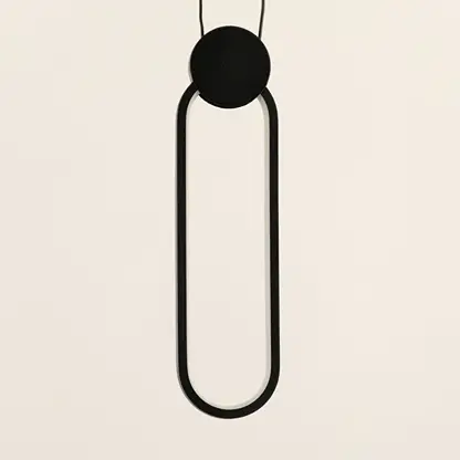 Minimal black pendant light with elongated oval frame and hanging cord placed against neutral wall background showcasing sleek contemporary lighting decor aesthetic.