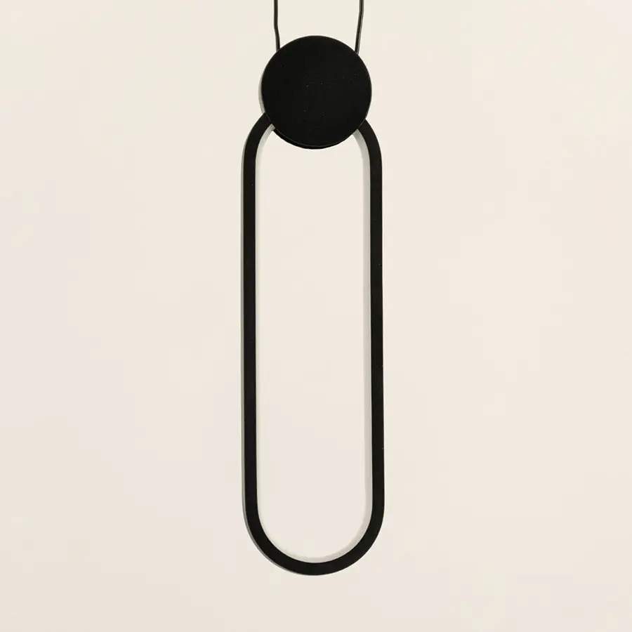 Minimal black pendant light with elongated oval frame and hanging cord placed against neutral wall background showcasing sleek contemporary lighting decor aesthetic.