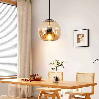 Amber glass and black metal pendant light adding warm elegance above the dining table in interiors.
