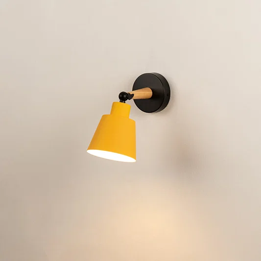 Yellow metal wall light with black mount on neutral background minimal modern lighting perfect for bedroom and living room decor.

