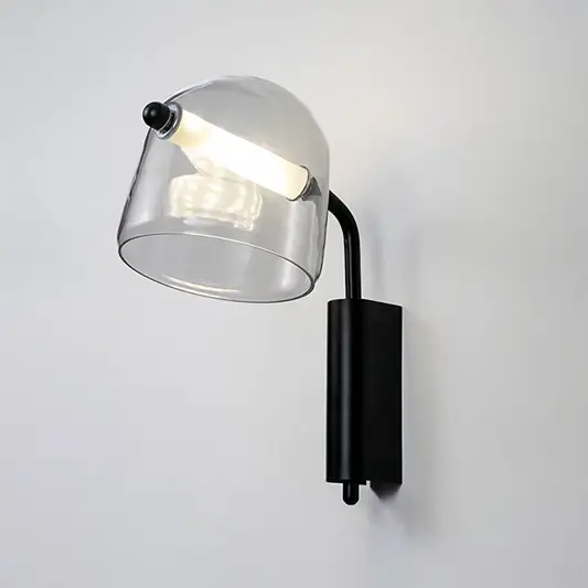 Modern clear glass wall light with black metal arm mounted on soft white wall background ideal for contemporary bedroom or living space lighting.