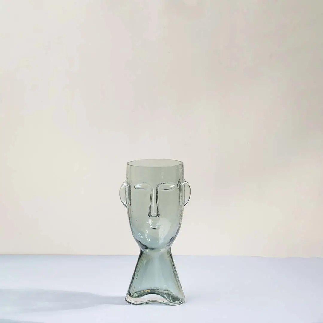Light green glass decorative vase with sculptural face design for tabletop styling and modern home decor displays.