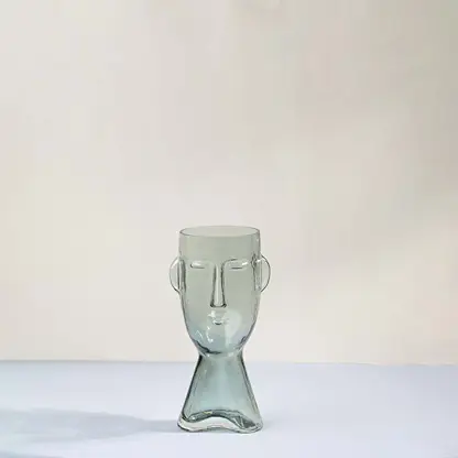 Light green glass decorative vase with sculptural face design for tabletop styling and modern home decor displays.