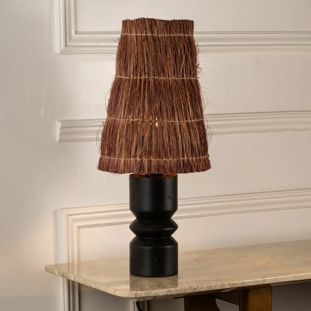 Black wood table lamp with woven brown fiber shade bringing rustic charm and natural texture to interior decor.