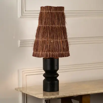 Black wood table lamp with woven brown fiber shade bringing rustic charm and natural texture to interior decor.