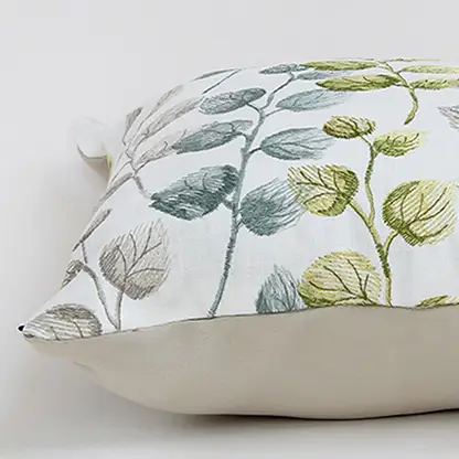 Soft cotton cushion cover with green and grey botanical design displayed at an angle providing a subtle nature inspired décor touch with a breathable gentle and skin friendly fabric finish.