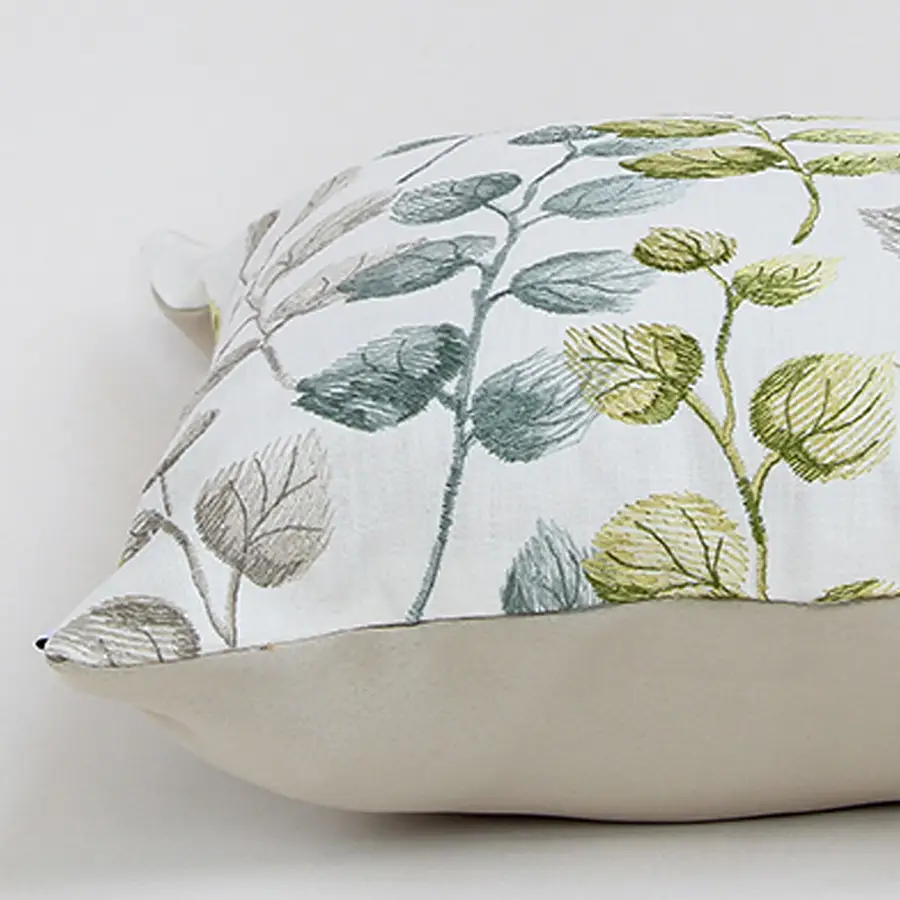 Soft cotton cushion cover with green and grey botanical design displayed at an angle providing a subtle nature inspired décor touch with a breathable gentle and skin friendly fabric finish.