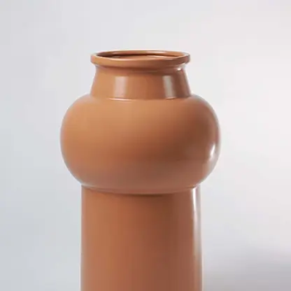 Closeup of sculptural brown ceramic vase displaying fine texture and smooth rounded detailing reflecting expert ceramic craftsmanship.