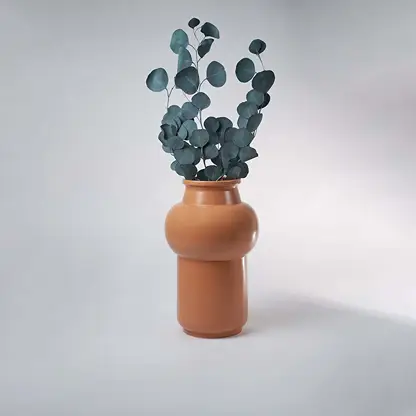Matte terracotta orange ceramic vase styled with green eucalyptus leaves on white background for organic modern art.