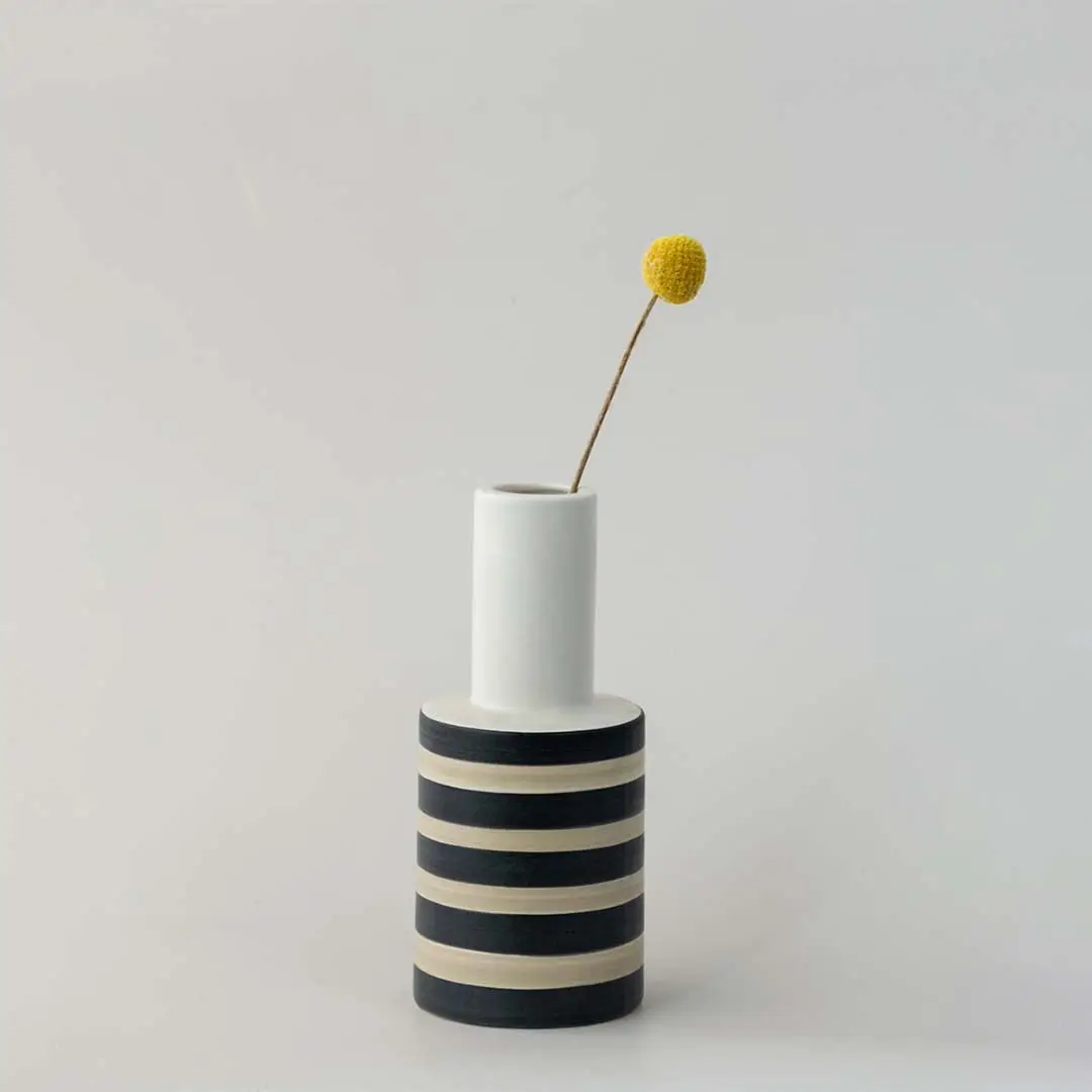 White ceramic decorative vase with black stripes and gold detail for tabletop styling and modern home decor.