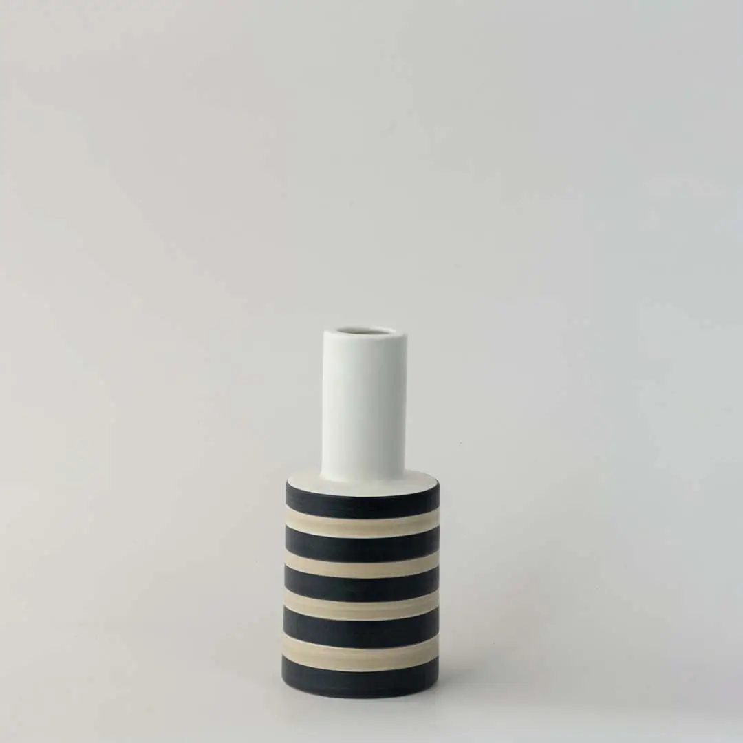 Modern striped ceramic vase with black and beige detailing photographed on a clean white background.