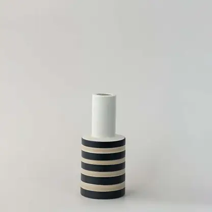 Modern striped ceramic vase with black and beige detailing photographed on a clean white background.