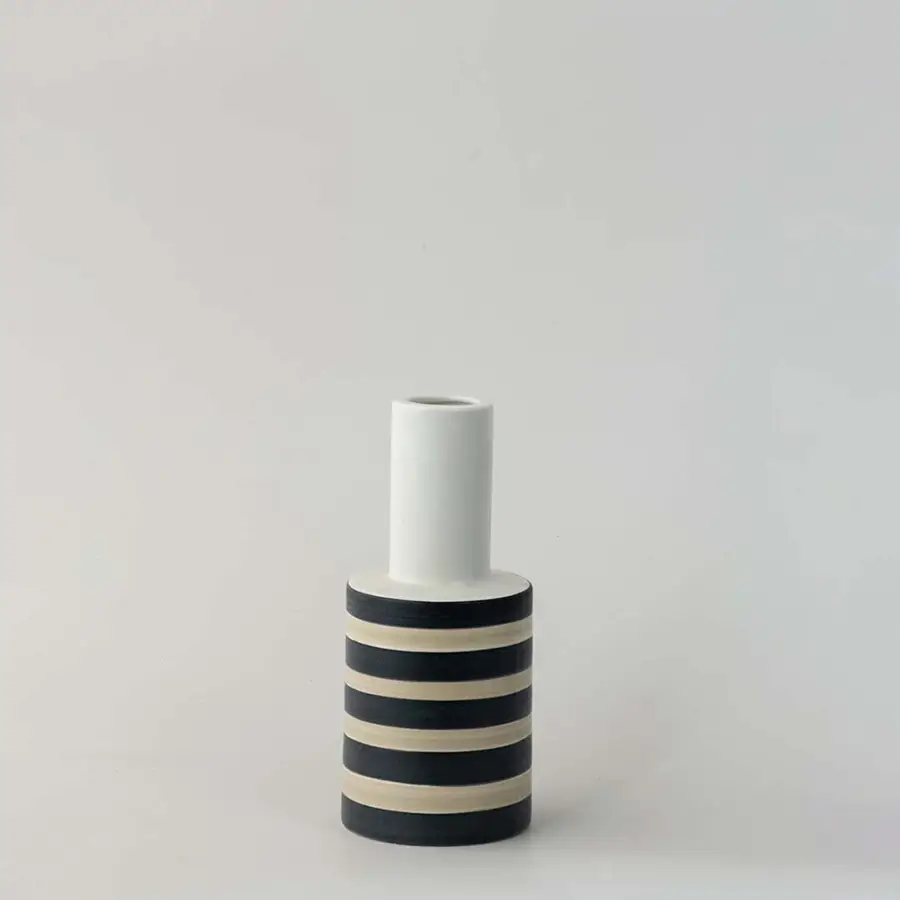 Modern striped ceramic vase with black and beige detailing photographed on a clean white background.